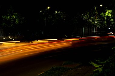 Karanlık bir gecede, Araba Işığı şehir caddesinde yol alır. Fotoğraf uzun pozla çekilir..