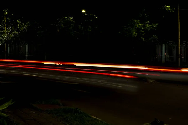 在漆黑的夜晚 灯光在城市街道上的小径上穿行 照片是长时间曝光后拍摄的 — 图库照片