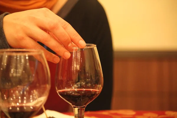 Sosteniendo una copa de vino en una mesa . — Foto de Stock