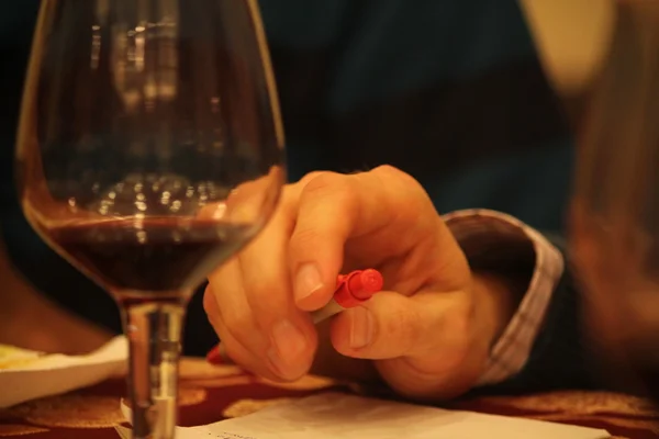 Trzymając kieliszek do wina w tabeli. — Zdjęcie stockowe