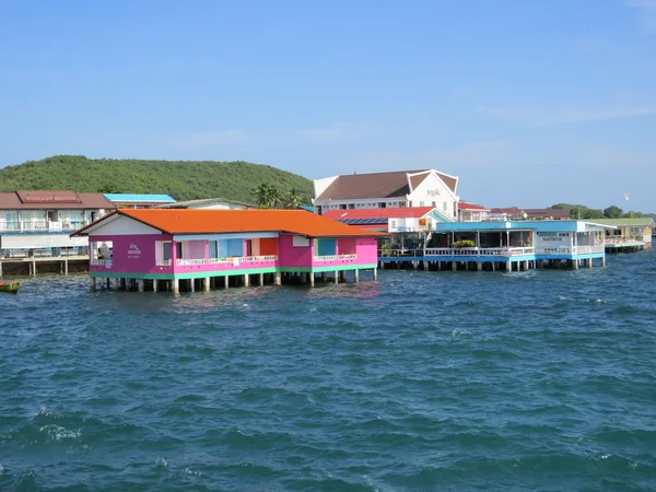 Budovy postavené na dřevěných pilotách v moři nedaleko kotviště trajektu v ostrově Koh Larn. — Stock fotografie