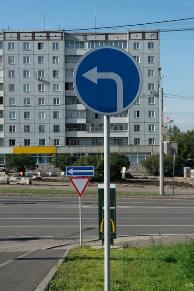 Panneau de signalisation rond bleu sur un pilier avec une flèche blanche. — Photo