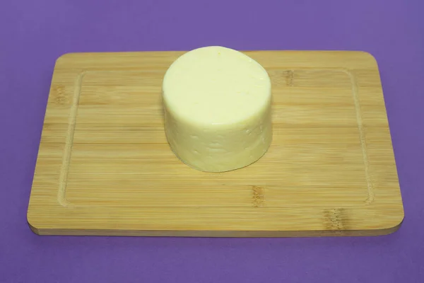 Head of cheese on a wooden cutting board.