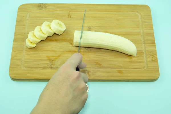 Skär en skalad banan med kökskniv. — Stockfoto