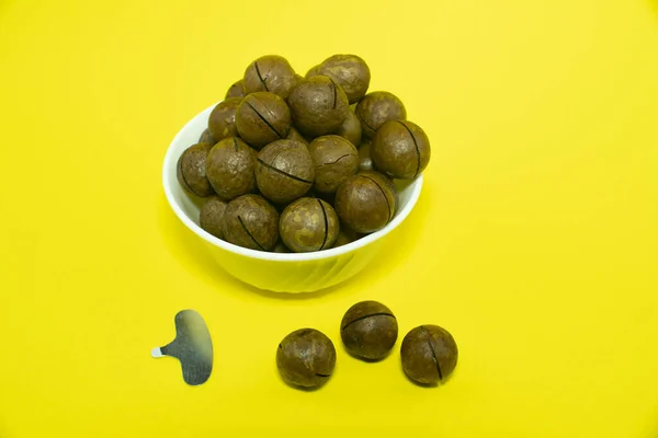 Macadam noten in een witte beker geïsoleerd op gele achtergrond. — Stockfoto