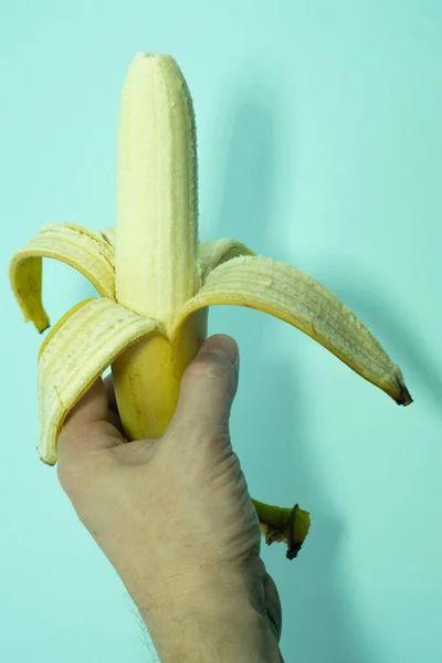 Una banana mezza pelata in una mano umana. — Foto Stock