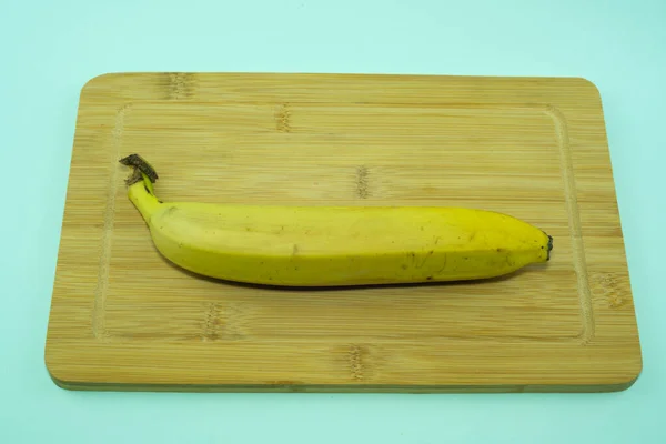 Skärbräda med banan isolerad på blå bakgrund. — Stockfoto