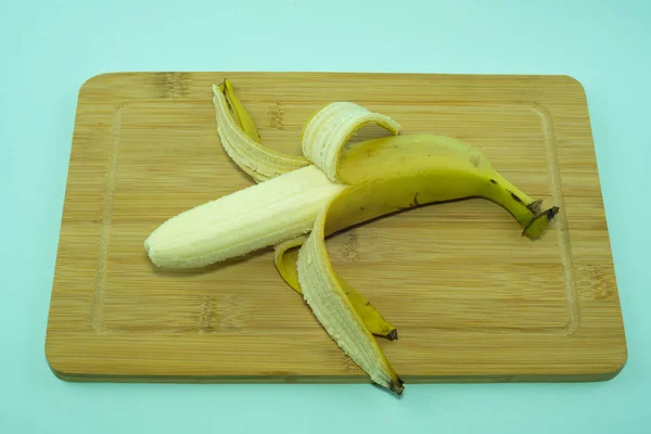 Banane, pelée en deux sur une planche à découper. — Photo