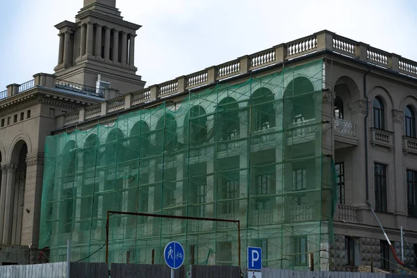 Фасад здания закрыт зеленой сеткой для ремонта. — стоковое фото