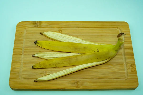 Банановая кожура на разделочной доске на синем фоне. — стоковое фото