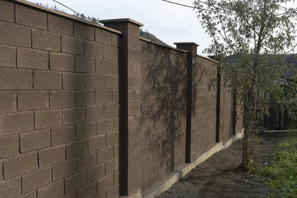 Eine dicke Backsteinmauer eines braunen Zauns eines Wohnhauses. — Stockfoto