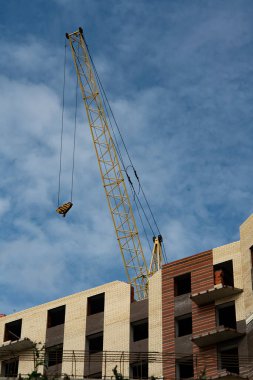 Sarı vinci olan çok katlı tuğladan bir ev..