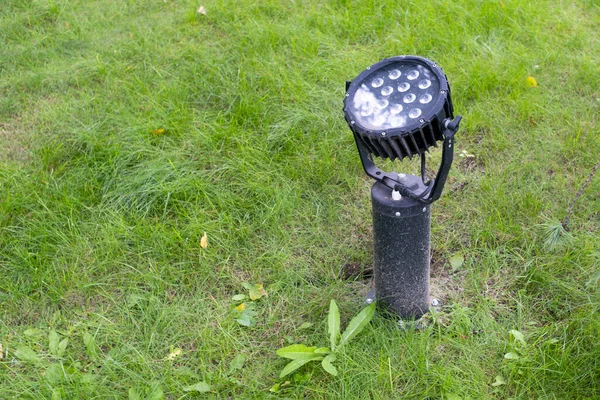 Lamp for night architectural lighting of buildings, fixed on a green lawn.