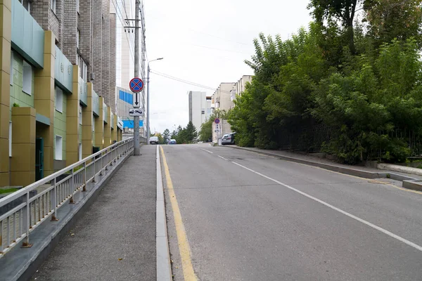 City road with markings and pedestrian zone along the building.