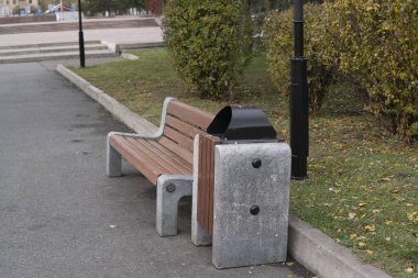 Kamu parkında çöp bidonlarıyla ahşap bank..