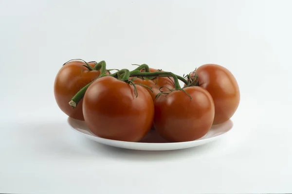 Close-up de tomates vermelhos em uma placa branca. — Fotografia de Stock