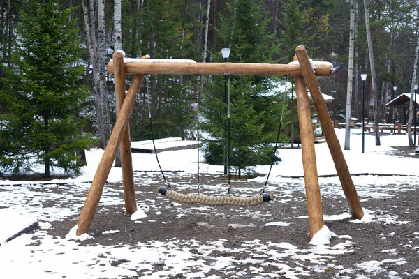 At the beginning of winter, a wooden swing in a snow-covered national park. — Stock Photo, Image