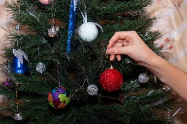 Bir kadının eli Noel ağacına parlak bir top asar..