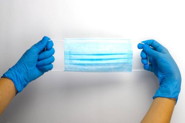 Koruyucu tıbbi maske mavi eldivenli ellerde..