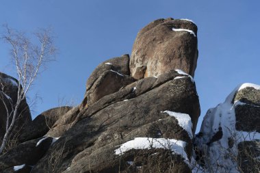 Nadir, kısmen yıpranmış karlı kahverengi bir kaya..
