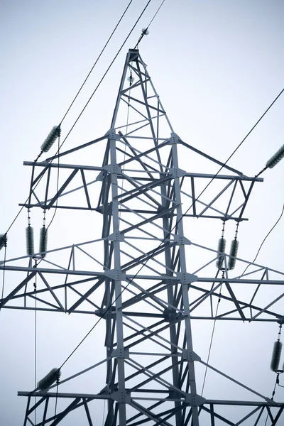 Metal electric pole against the background of the cloudy sky.