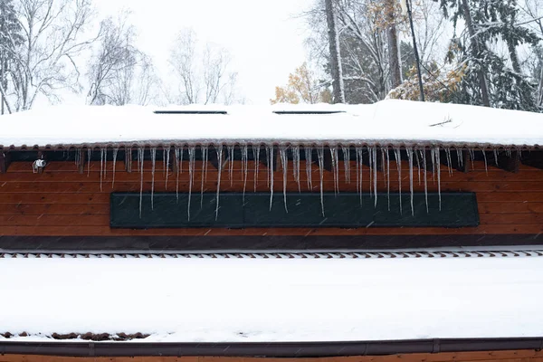 Une longue rangée de glaçons sur le toit du bâtiment. — Photo