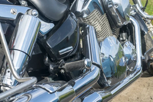 Zwarte motorfiets voetsteun onder chromen motoronderdelen. — Stockfoto