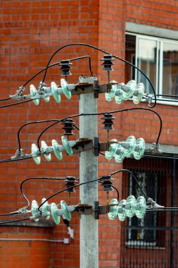 Duvarın arka planında cam yalıtıcılarla elektrik direği var..