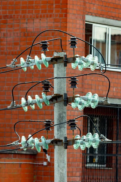 Duvarın arka planında cam yalıtıcılarla elektrik direği var..