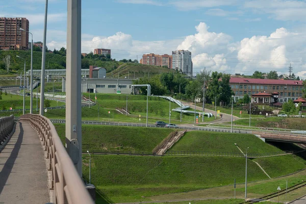Un'autostrada con un cavalcavia sullo sfondo di una città industriale lungo il fiume. — Foto Stock