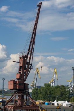 Endüstriyel bir şehrin arka planında büyük bir kırmızı liman vinci.