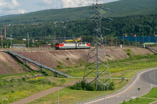 Ηλεκτρική ατμομηχανή σε σιδηροδρομικές γραμμές με φόντο ορεινό έδαφος. — Φωτογραφία Αρχείου