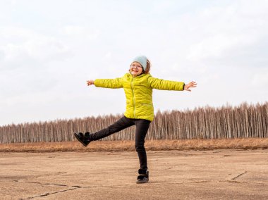 Parlak ceketli neşeli kız baharda ormanın arka planında