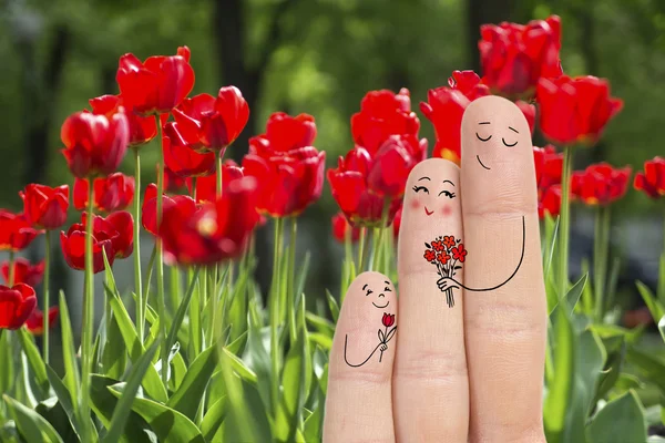 Konzeptionelle Familienfingerkunst. Vater und Sohn überreichen seiner Mutter Blumen. Archivbild. — Stockfoto