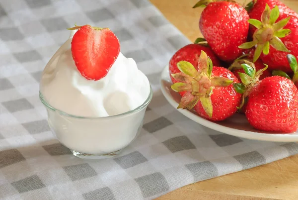 Érett szamóca fehér tányéron és tejszínnel az asztalon — Stock Fotó
