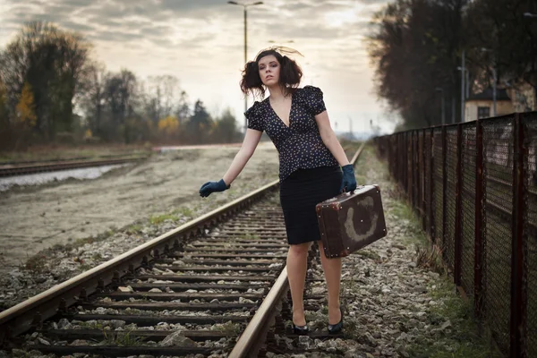 Chica esperando el tren en la plataforma de ferrocarril vacía —  Fotos de Stock
