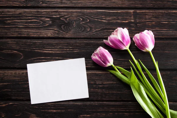 Tulpen en een kaart op een hout — Stockfoto