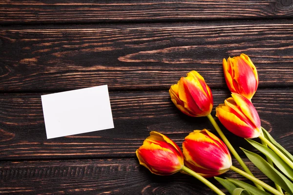 Tulpen en een kaart op een hout — Stockfoto