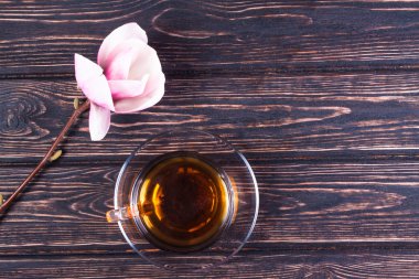 Fincan siyah çay ve çiçek Manolya ahşap kurullarında.