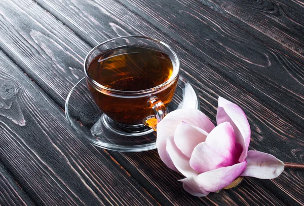 Fincan siyah çay ve çiçek Manolya ahşap kurullarında.