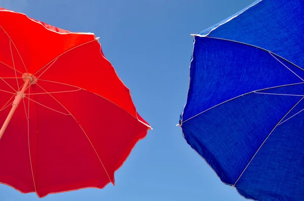 Guarda-chuva de praia vermelho e azul e céu azul acima — Fotografia de Stock