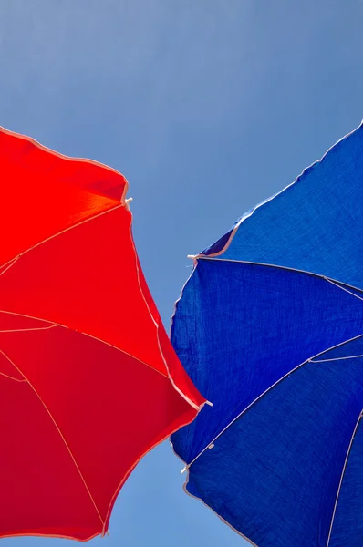 Red and blue beach umbrella and blue sky above