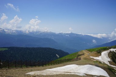 Bulutların üzerinde kar olan güzel yeşil dağlar. Rosa Khutor. Yaz
