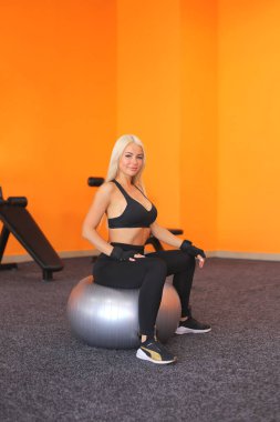 Güzel eğitmen kadın topla esneme egzersizi yapıyor. Spor topuyla egzersiz yapan genç bir kadın. Sağlıklı bir yaşam tarzı. Spor motivasyonu, spor anlayışı.