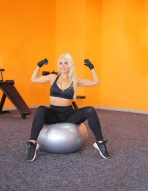 Güzel eğitmen kadın topla esneme egzersizi yapıyor. Spor topuyla egzersiz yapan genç bir kadın. Sağlıklı bir yaşam tarzı. Spor motivasyonu, spor anlayışı.