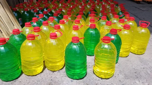 Several plastic gallons with red lid. many plastic gallons of colored liquid. plastic gallons with soap, with shampoo. wholesale gallon warehouse