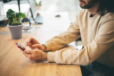 Ofiste cep telefonu kullanan sakallı adam.