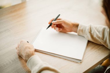 Adam elleri boş bir deftere yazıyor.