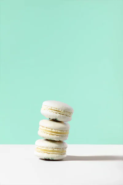 Pile de macarons vanille sur fond vert Image En Vente