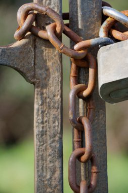 Paslı zinciri ve metal kapıdaki asma kilidi kapatın.